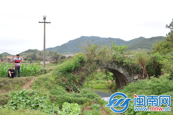 已廢棄的石拱橋，被野草覆蓋，下有溪流，村民稱此路